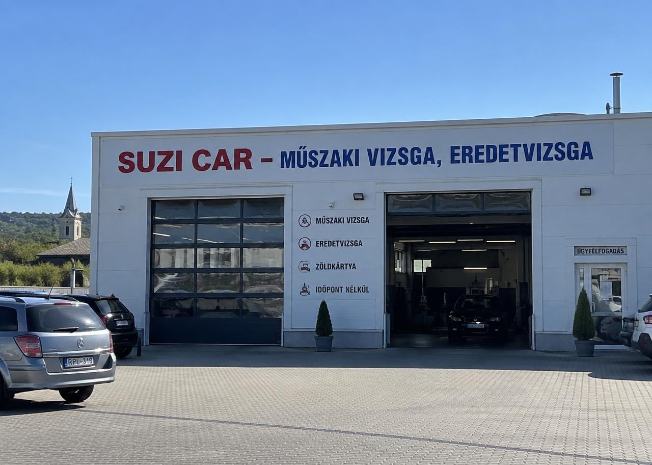 A Suzi-Car fehér szervizcsarnoka „SUZI CAR – MŰSZAKI VIZSGA, EREDETVIZSGA” felirattal